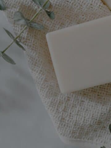 zinc pyrithione bar for skin on a white cloth surrounded by eucalyptus.